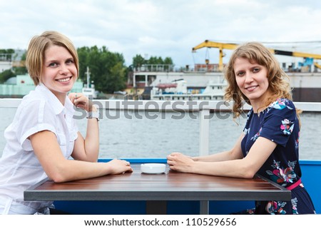 Two girlfriends on different side of table