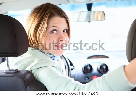 Joyful woman inside of car looking back from driver seat