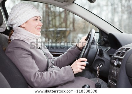 Woman in winter clothes driving a car looking forward