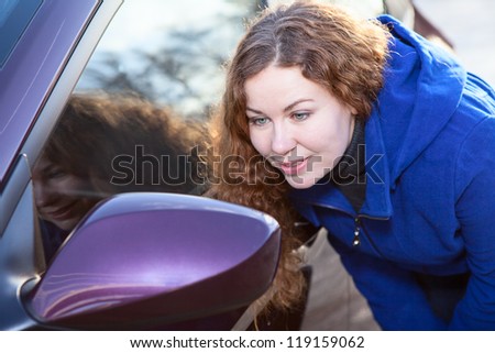 Curly hair woman looking in car back side mirror against sunlights