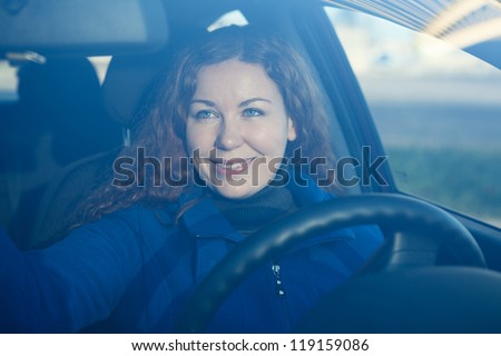 Pretty woman in car preparing to driving correcting back mirror