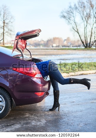 Woman body into car luggage trunk. Legs sticking out