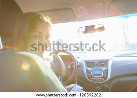 Looking back and sitting inside of car woman with sun rays in window