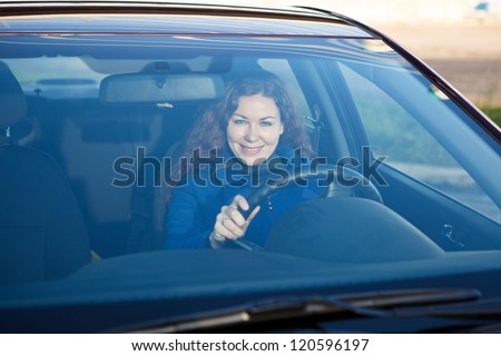 Attractive driver inside of car smiling through the windshield