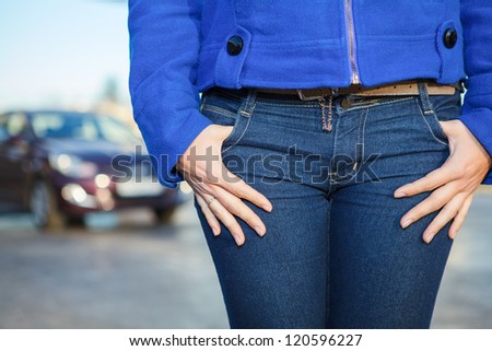 Women hands in jeans pockets and vehicle on background