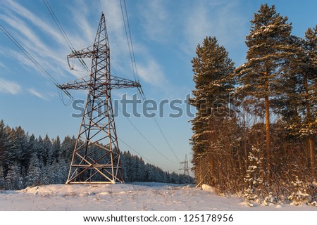 Power electric high-voltage poles in winter evergreen forest