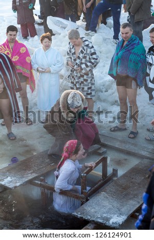 SAINT-PETERSBURG, RUSSIA-JANUARY 19: Woman in ice-hole dip three times in Epiphany celebration on January 19, 2013 in Saint-Petersburg, Russia.  Orthodox tradition in Epiphany (Holy Baptism)