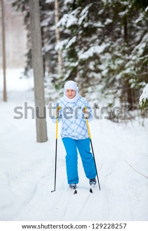 Happy Caucasian woman skiing in wintry forest alone