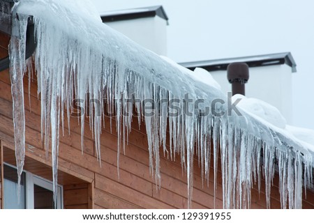 Roof of the house with snow and icicles overhanging