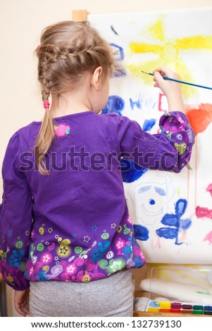 Small Caucasian child painting with brush and paint