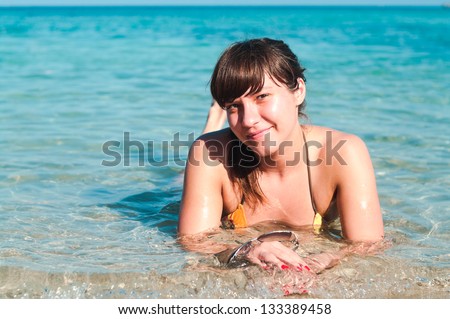 Portrait of a happy young woman in bikini laying in sea. Copyspace