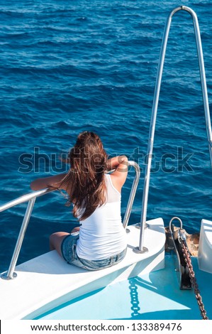 Brunette woman on bow of yacht with legs out