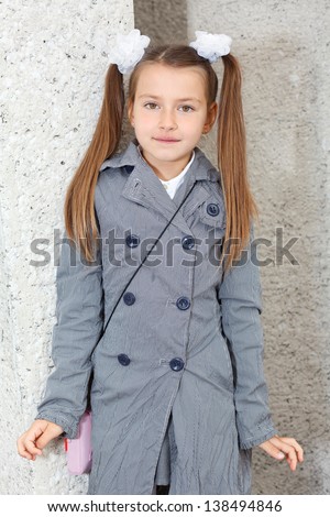 Portrait of a young Caucasian girl with long tails in a gray coat.