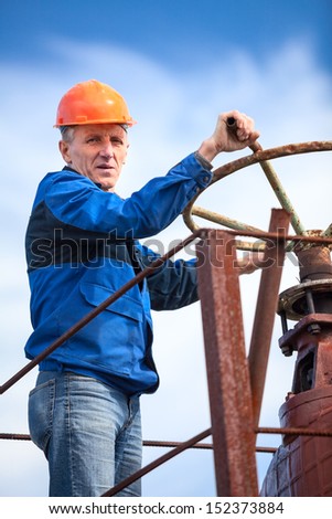 Senior manual worker turning huge valve gate at factory