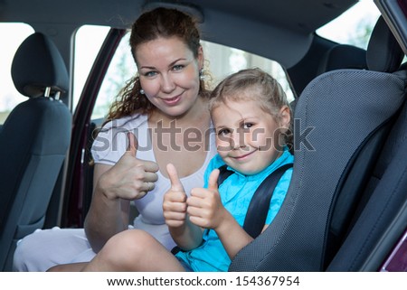 Mother and child showing thumb up gesture in car safety seat Mother and child showing thumb up gesture in car safety seat