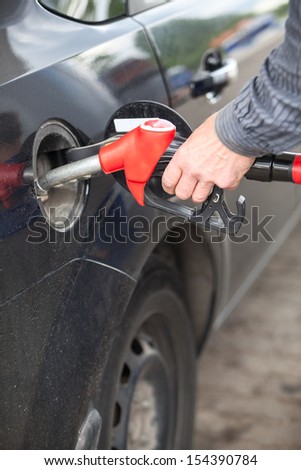 Male hand refilling the car with fuel on a filling station