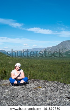 Woman sitting on mountain top and looking at camera