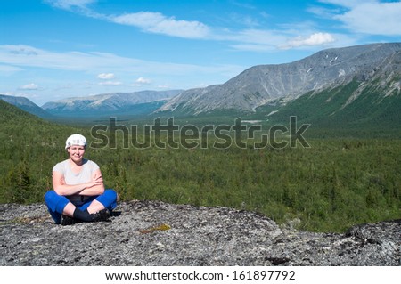 Woman sitting on mountain top and looking at camera. Copy space