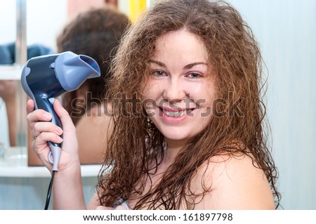 Excited Caucasian woman drying her hair with hairdryer