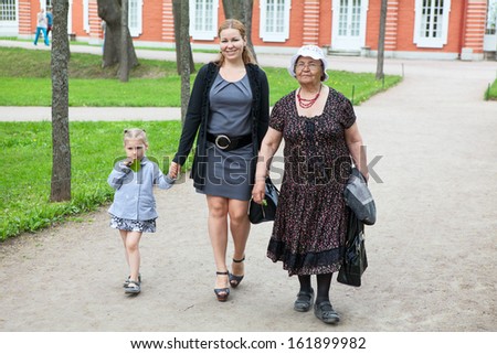 Grandmother, mother and young daughter walking in park at summer season