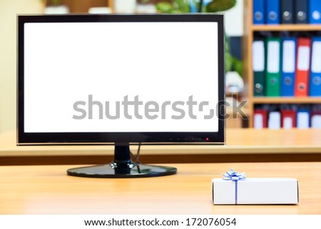 Isolated monitor and small gift box on the office desk