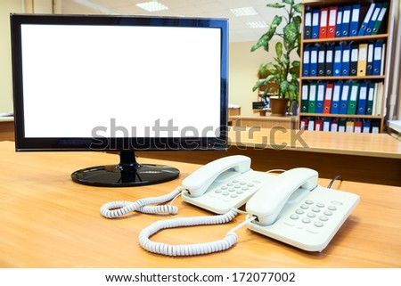 Monitor with isolated on white screen with telephones on desk in office