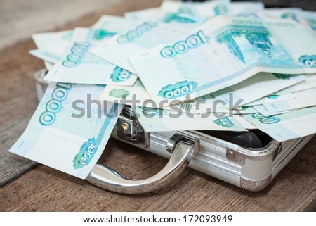 Opened steel case with Russian banknotes inside on wooden floor