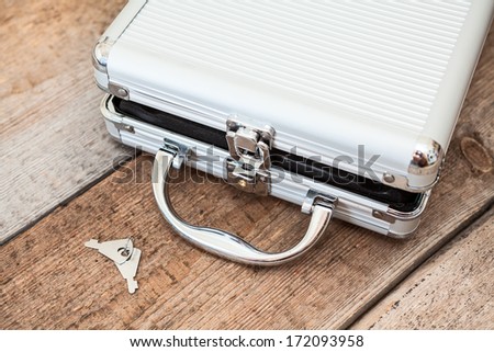 Aluminum opened suitcase with keys on wooden floor