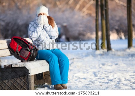 Woman with backpack heating hands in mittens at winter, copyspace