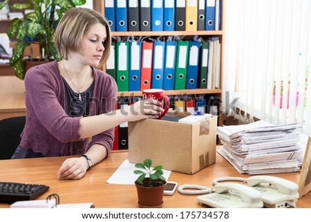 Fired office employee packing personal belongings in box