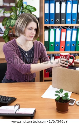 Woman collects things in a cardboard box in the workplace