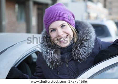 Happy pretty woman with an open car door in winter clothes