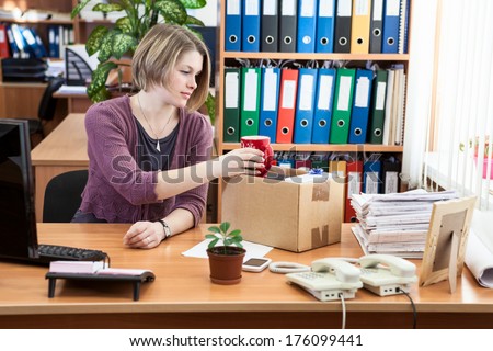 Fired woman collecting things in cardboard box in the workplace