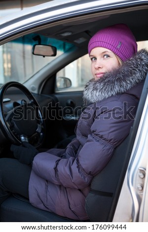Attractive young woman in winter clothes sitting in car