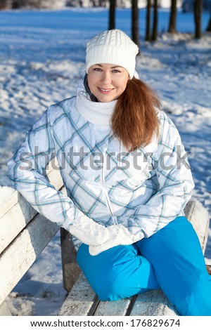 Happy woman sitting on park bench at winter season