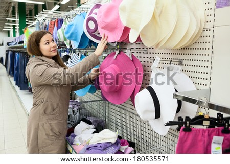 Woman looking for summer hats on shop shelf