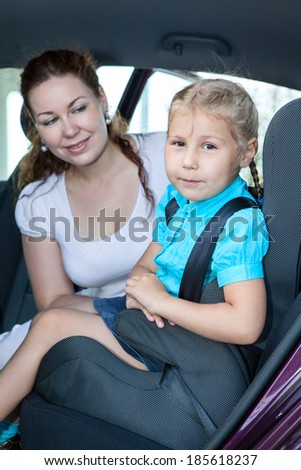 Mother with little daughter sitting on back seat of car