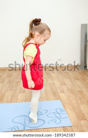 Little girl walking on tiptoe over sports mat