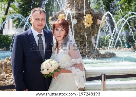 Bride and groom standing against fountain