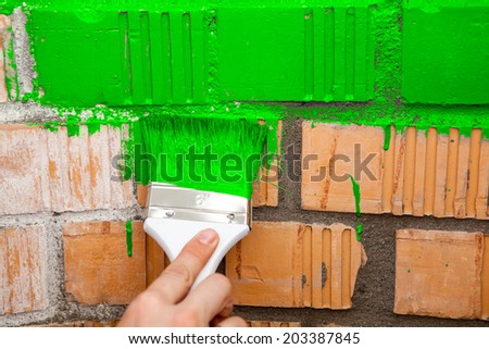 Paint brush with green color on brick wall