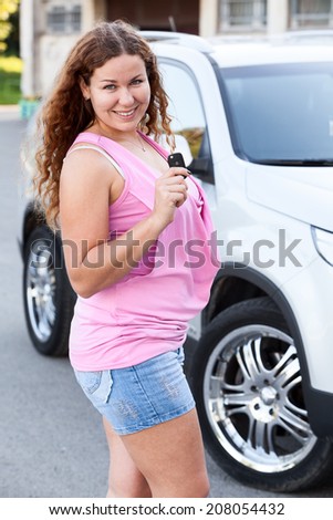 Woman in pink clothes standing in front of car with ignition key