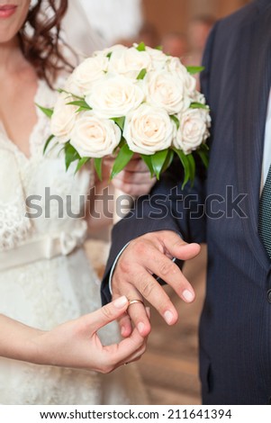 Woman wearing wedding ring on groom finger