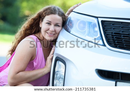 Pretty girl sitting her cheek against to the bumper of the car