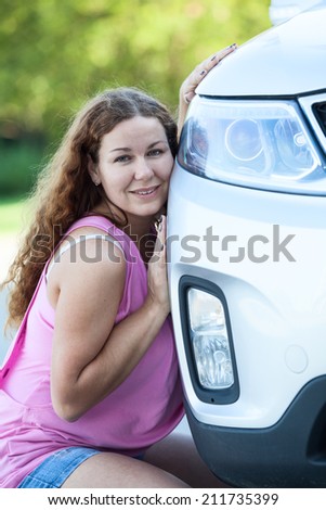 Attractive woman in pink blouse leaning her cheek to the car