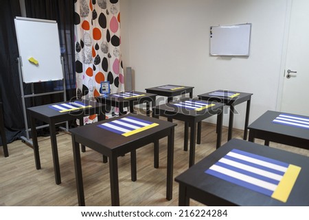 Interior of small business meeting room with decks and flipchart. Nobody