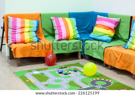 Corner sofa with colorful striped pillows, balloons on the floor in the room