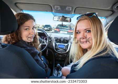 Two Caucasian women sitting inside of car when driving, looking back