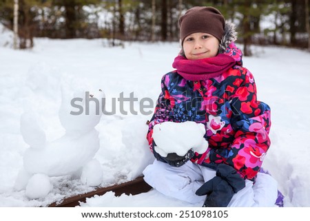 Happy smiling girl sitting with god snowman at winter season