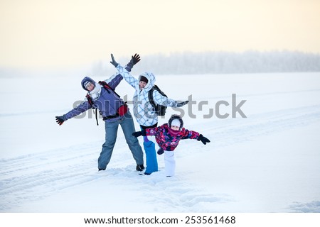 Happy laughing mature woman, young woman and girl posing on frozen winter lake