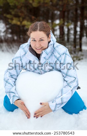 Lovely woman with snow heart hugging with hands, winter season